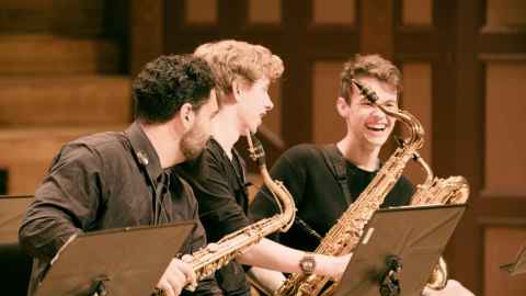 three jazz students laughing with their instruments at a rehearsal